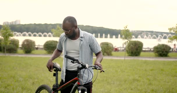 Kamu parkında bisikletli siyah bir adam — Stok video