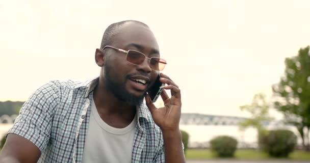 Orang kulit hitam berbicara lewat telepon berdiri di taman — Stok Video