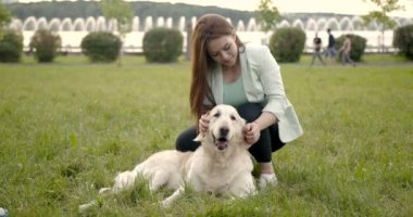 Sevecen bir kadın parkta bir golden retriever 'ı okşuyor.