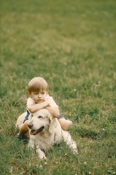 Pequeño niño jugando con su perro en una hierba — Foto de Stock