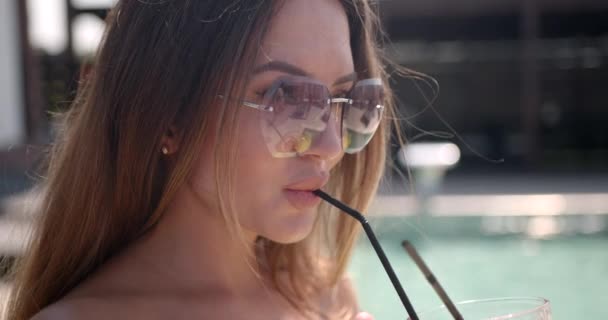 Mujer bonita bebiendo un cóctel en una piscina — Vídeos de Stock