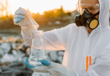 Yakın plan bilim adamı zehirli kimyasalları kirli zeminde inceliyor.