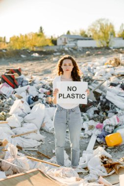 Çöplükte plastik tabela bulunmayan genç bir kadın.