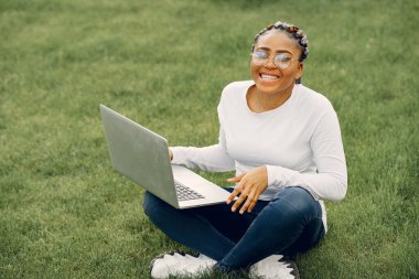 Yazlık bir şehirde dizüstü bilgisayarı olan siyah bir kız.