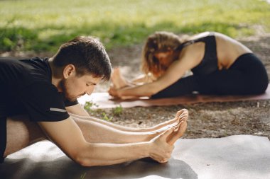 Erkek ve kadın parkta yoga egzersizleri yapıyorlar.