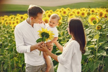 Anne, baba ve oğul ayçiçeği tarlasında beyaz elbiseli.
