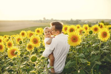 Baba, ayçiçeği tarlasında dikilirken oğluna sarılıyor.