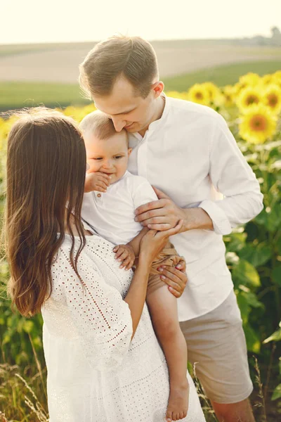 Anne, baba ve oğul ayçiçeği tarlasında beyaz elbiseli.