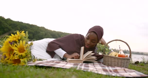 身穿白衣的黑人妇女在河边看书 — 图库视频影像