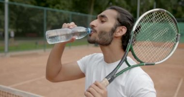 Tenis kortunda suyu olan yakışıklı bir tenisçi.