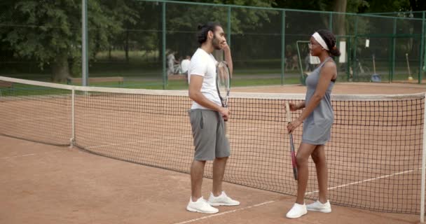 Πολυφυλετικός άνδρας και γυναίκα μιλώντας στο γήπεδο τένις — Αρχείο Βίντεο