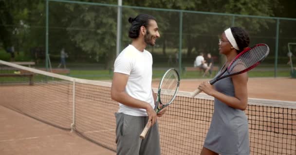 Multiracionális férfi és nő beszél a teniszpályán — Stock videók