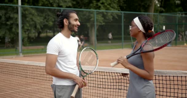 Uomo e donna multirazziale che parlano sul campo da tennis — Video Stock