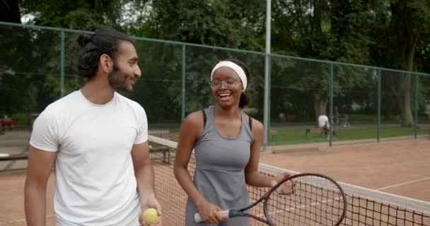 Multi etnikai férfi és nő a sportruházatban beszél tenisz az udvaron — Stock videók