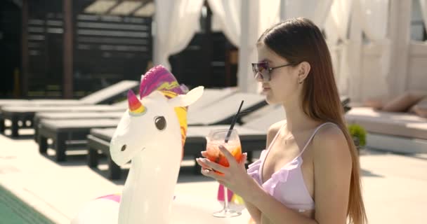 Підліток красива дівчина з коктейлем розслабляється біля басейну — стокове відео