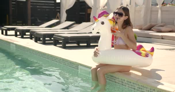 Menina bonita adolescente com coquetel relaxante à beira da piscina — Vídeo de Stock