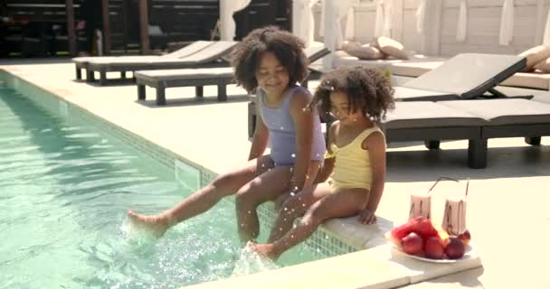Deux petites filles assises au bord de la piscine et mangeant de la pastèque — Video