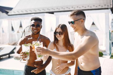 Mayolu üç arkadaş yüzme havuzunun yanında kokteyl içerek rahatlıyor.