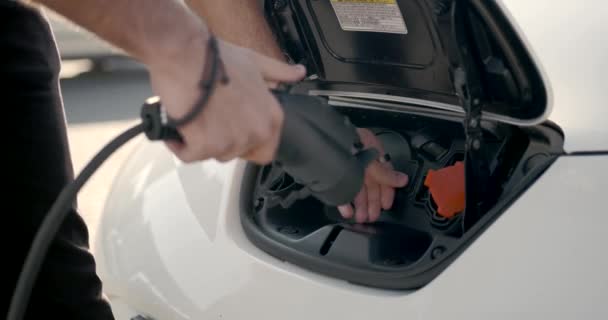 Jeune homme arabe recharge voiture électrique blanche au parking — Video