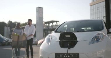 Çok ırklı bir çift alışveriş yaptıktan sonra arabadan para alıyor.