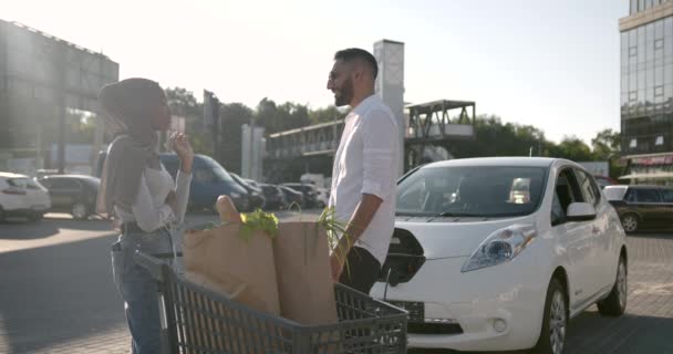 Multi coppia etnica carica auto elettrica dopo lo shopping — Video Stock