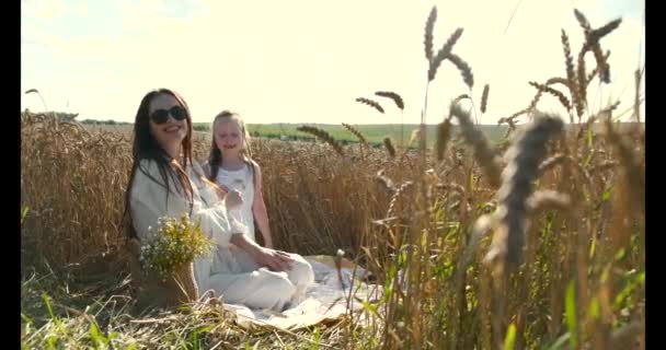 Schöne Mutter und Tochter haben Spaß in einem Weizenfeld bei Sonnenuntergang — Stockvideo