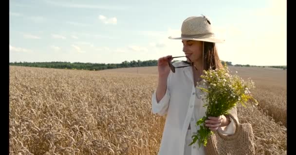 Stylish woman with bunch of flowers in wheat field — Stock Video