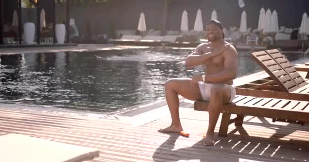 Preto jovem colocando protetor solar na piscina resort — Vídeo de Stock