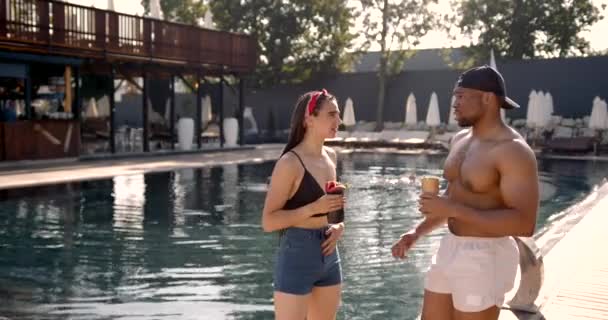 Zwarte man flirten met een aantrekkelijke vrouw bij het zwembad — Stockvideo