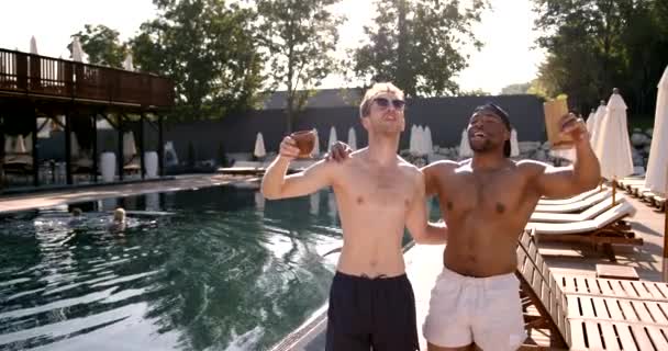 Sorrindo amigos do sexo masculino desfrutando de coquetéis perto da piscina — Vídeo de Stock