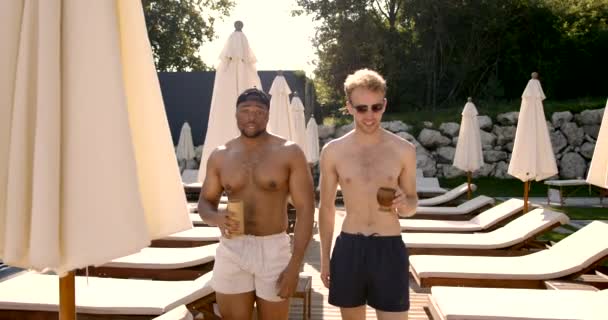 Leende manliga vänner njuter av cocktails nära poolen — Stockvideo