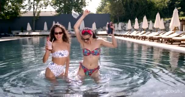 Twee vrouwelijke vrienden ontspannen bij het zwembad in de zomer — Stockvideo