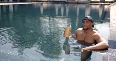 Yüzme havuzunda kokteyl içen genç bir zenci.