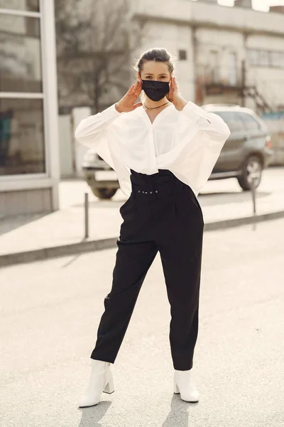 Een vrouw met een masker staat op straat — Stockfoto