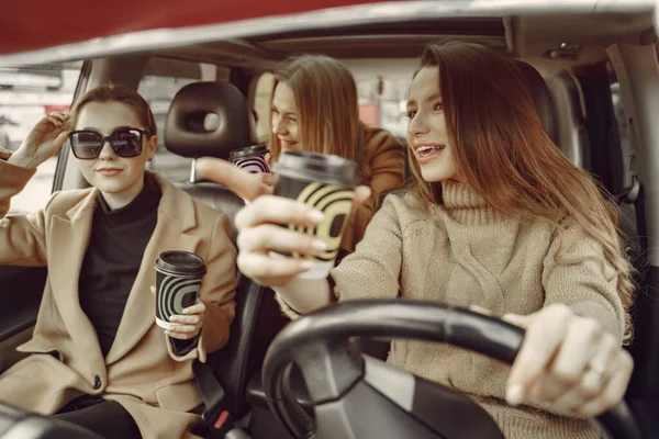 Tres chicas sentadas dentro del coche y tomando un café — Foto de Stock