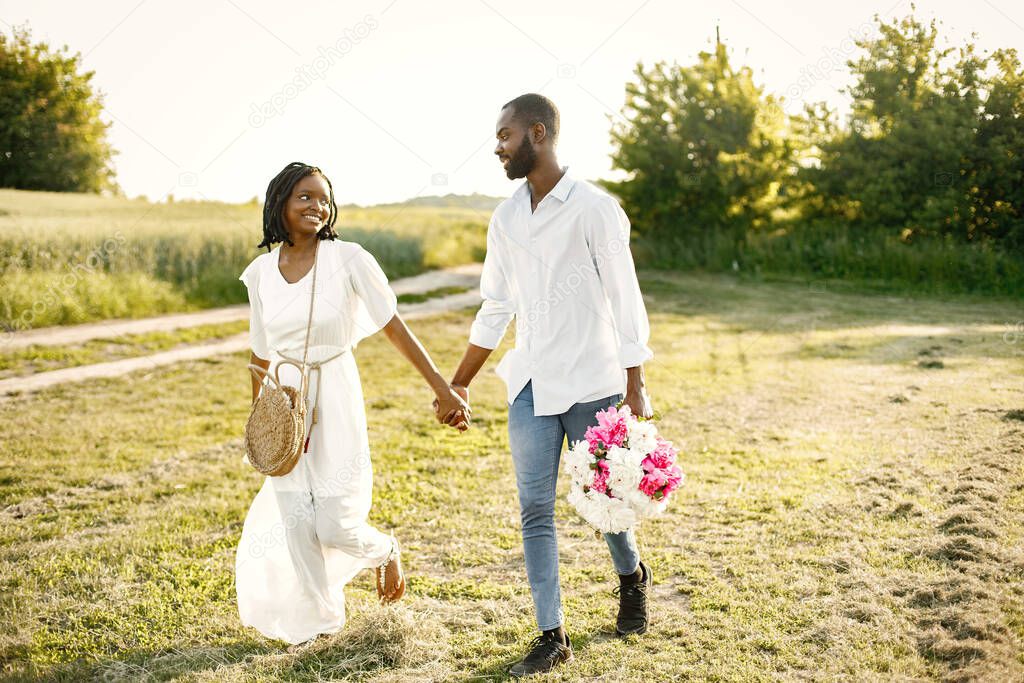 African newlyweds walking with bouquet in nature