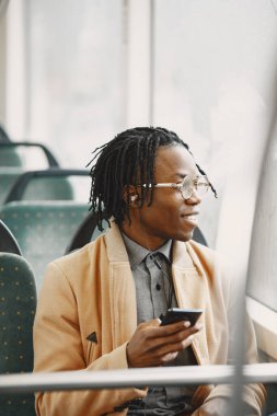 Genç Afrikalı işadamı otobüste oturuyor.