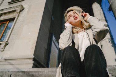 Sarışın, yaz şehrinde müzik dinliyor.