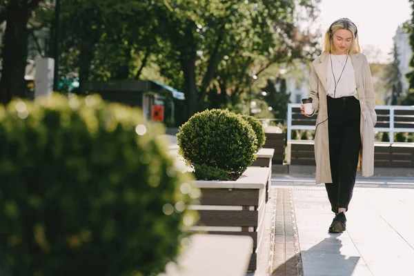 Блондинка гуляет по летнему городу за чашкой кофе — стоковое фото