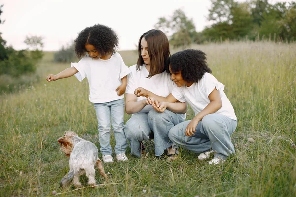 Mère caucasienne et ses filles métisses nourrissent un Yorkshire Terrier — Photo