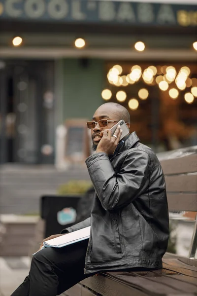 Schwarzer sitzt auf einer Bank und benutzt ein Telefon — Stockfoto
