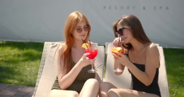 Mayo giymiş, kokteylli iki kız dinleniyor.