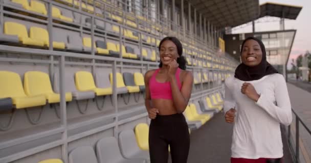 Svarta sportiga tjejer joggar nära stadion rader — Stockvideo