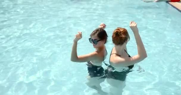 Duas meninas relaxando na piscina exterior com água azul — Vídeo de Stock