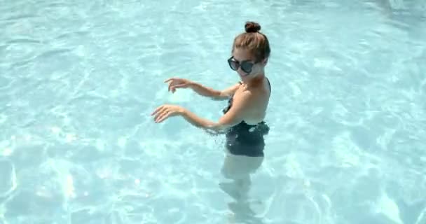 선글라스를 쓴 젊은 여자가물 공원의 수영장에서 춤을 추고 있다 — 비디오