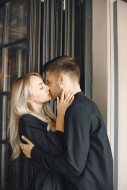 Romantik genç çift kafe vitrininde sarılıyor.