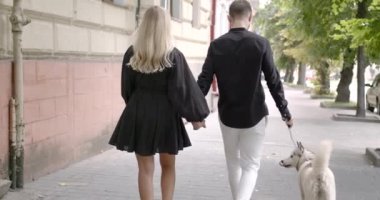 Bir adam ve bir kadın şehirde evcil hayvanlarıyla yürüyor.