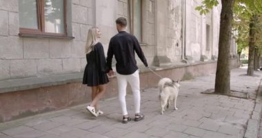 Bir adam ve bir kadın şehirde evcil hayvanlarıyla yürüyor.