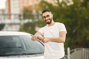 Hintli adam yıkamadan sonra araba yıkamada beyaz aracını siliyor.