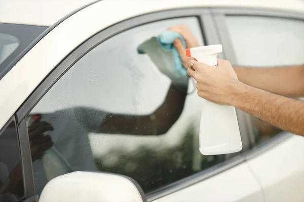 Foto recortada de las manos de un hombre con un fluido de pulido cerca de su coche — Foto de Stock